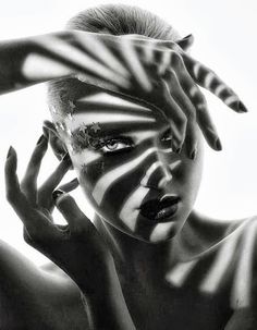 a woman with her hands on her head and face painted like zebra stripes, posing in front of a white background