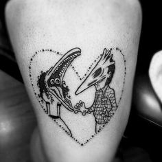 a black and white photo of two people in a heart shaped tattoo on the leg