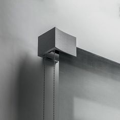 a shower head with a chain hanging from it's side next to a wall