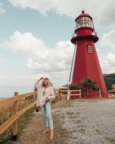 a woman standing in front of a red lighthouse