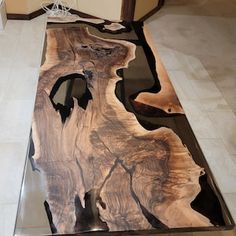 a table made out of wood and glass in the middle of a room with tile flooring