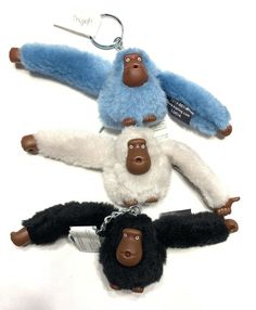 three stuffed animals hanging from hooks on a white surface, one is blue and the other is black