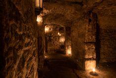 some lights that are on the side of a wall in a tunnel with stone walls