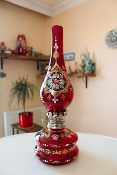 a red vase sitting on top of a white table