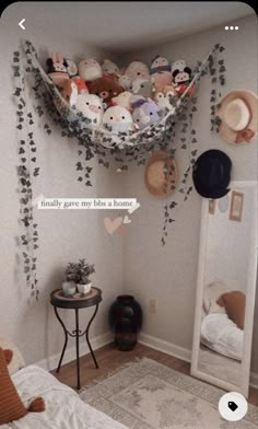 a bedroom with stuffed animals hanging from the ceiling and pillows on the wall above it