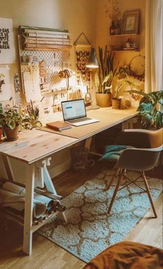 a desk with a laptop on top of it in a room filled with potted plants