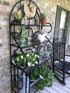 a shelf with potted plants on top of it next to a chair and table