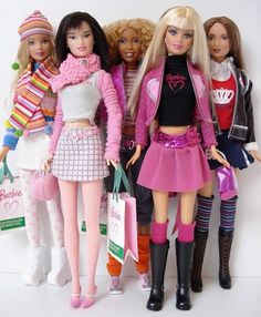 four barbie dolls standing next to each other