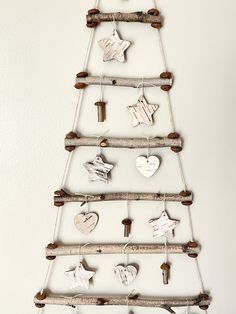 a christmas tree made out of branches with ornaments hanging from it's sides and wooden pegs