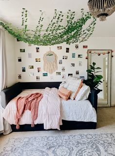 a bed with pillows and blankets on top of it next to a wall covered in pictures