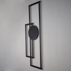 a clock mounted to the side of a white wall next to a black metal frame