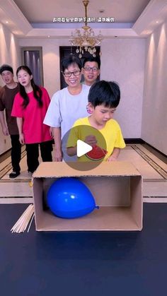 a group of people standing around a cardboard box with a blue ball in the middle