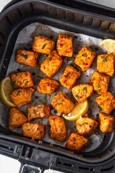 chicken cubes with lemon and parsley in an air fryer pan, ready to be cooked