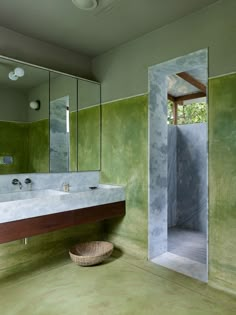 a bathroom with green walls and two sinks in the middle, along with a large mirror on the wall