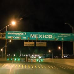 an exit sign is lit up at night on the freeway in front of some traffic lights