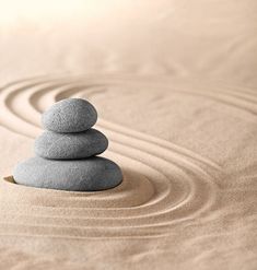 two rocks stacked on top of each other in the middle of a raked sand area