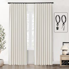 a white curtain hanging on the side of a window next to a potted plant