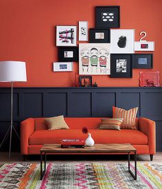 a living room with an orange couch and various pictures on the wall above it, along with a coffee table