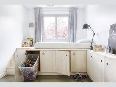 a bedroom with white walls and wooden cabinets in the corner is filled with toy cars