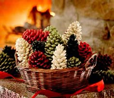 a basket filled with pine cones sitting on top of a stone wall next to a fire place