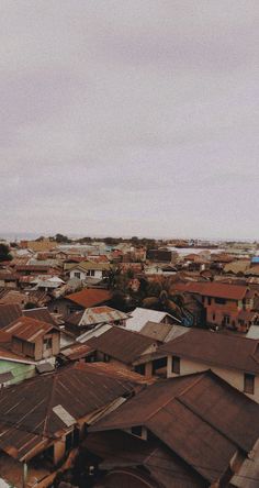 an aerial view of a city with rooftops and houses in the foreground, on a cloudy day