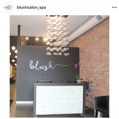 a hair salon with a black and white reception desk in front of a brick wall