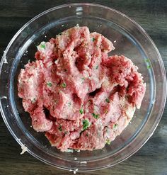 a glass bowl filled with meat on top of a wooden table