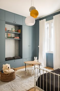 a child's room with blue walls and white carpet, including a teddy bear on the floor