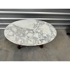 a white marble topped table with wheels on the bottom and two legs, sitting in front of