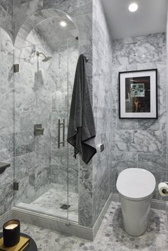 a white toilet sitting next to a walk in shower under a framed picture on the wall