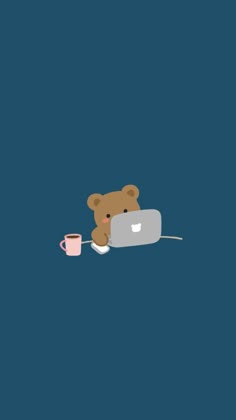 a brown teddy bear sitting on top of a laptop computer next to a cup of coffee