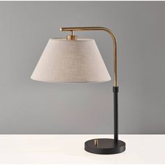 a table lamp with a white shade on it and a black stand next to it