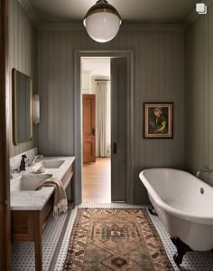 a bathroom with a bathtub, sink and rug on the floor in front of it