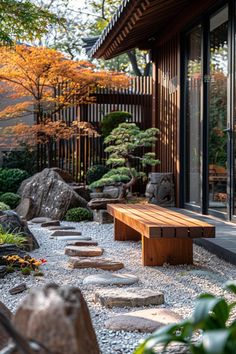 a wooden bench sitting in the middle of a garden next to rocks and trees with orange leaves