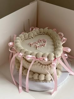 a heart shaped cake with pink ribbon on top in a card board box for someone's 50th birthday