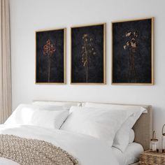 two paintings on the wall above a bed in a bedroom with white linens and pillows