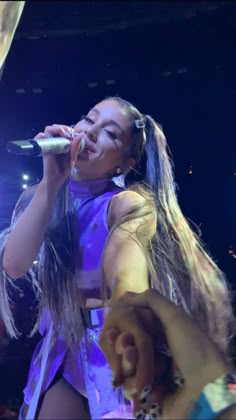 a woman with long hair singing into a microphone