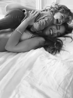 two women laying on top of each other on a bed