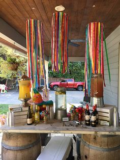 an outdoor bar with colorful streamers hanging from it's ceiling and wine bottles on the table