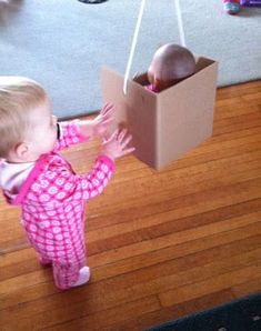 a toddler playing with an egg in a box