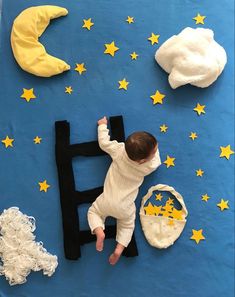 a baby laying on top of a blue blanket next to stars and moon decorations in the sky