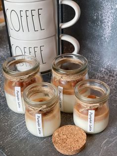 four jars filled with coffee sitting next to a cup