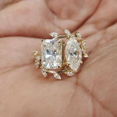 a person holding an engagement ring with two pear shaped diamonds on it's side