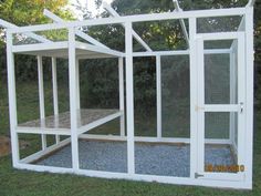 a white chicken coop in the grass