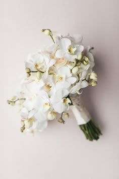 a bridal bouquet with white orchids on a pale pink background, top view