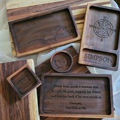 three wooden trays with engraved names and pictures on them, one has a compass