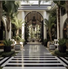 the entrance to a hotel with black and white striped flooring, potted plants and palm trees