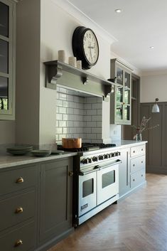 a clock mounted on the wall above an oven in a kitchen