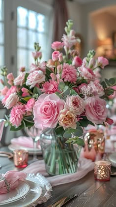 a vase filled with pink flowers sitting on top of a table next to plates and cups