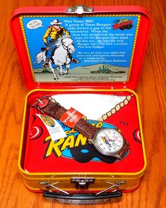 an open tin box with a watch in it